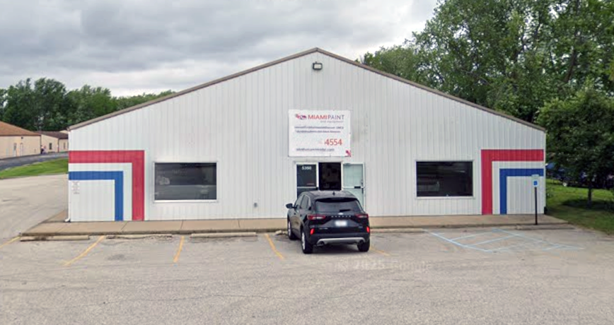 White commercial building with red and blue trim and "Manapaint" signage at 4554, dark SUV parked in front, Cincinnati Ohio